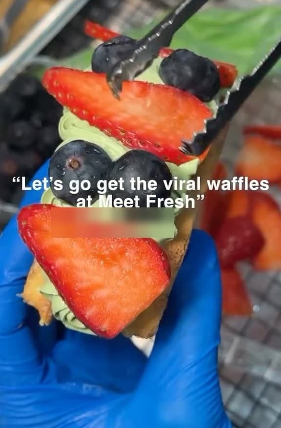 A matcha-cream waffle layered with sliced strawberries and blueberries — the viral waffle.